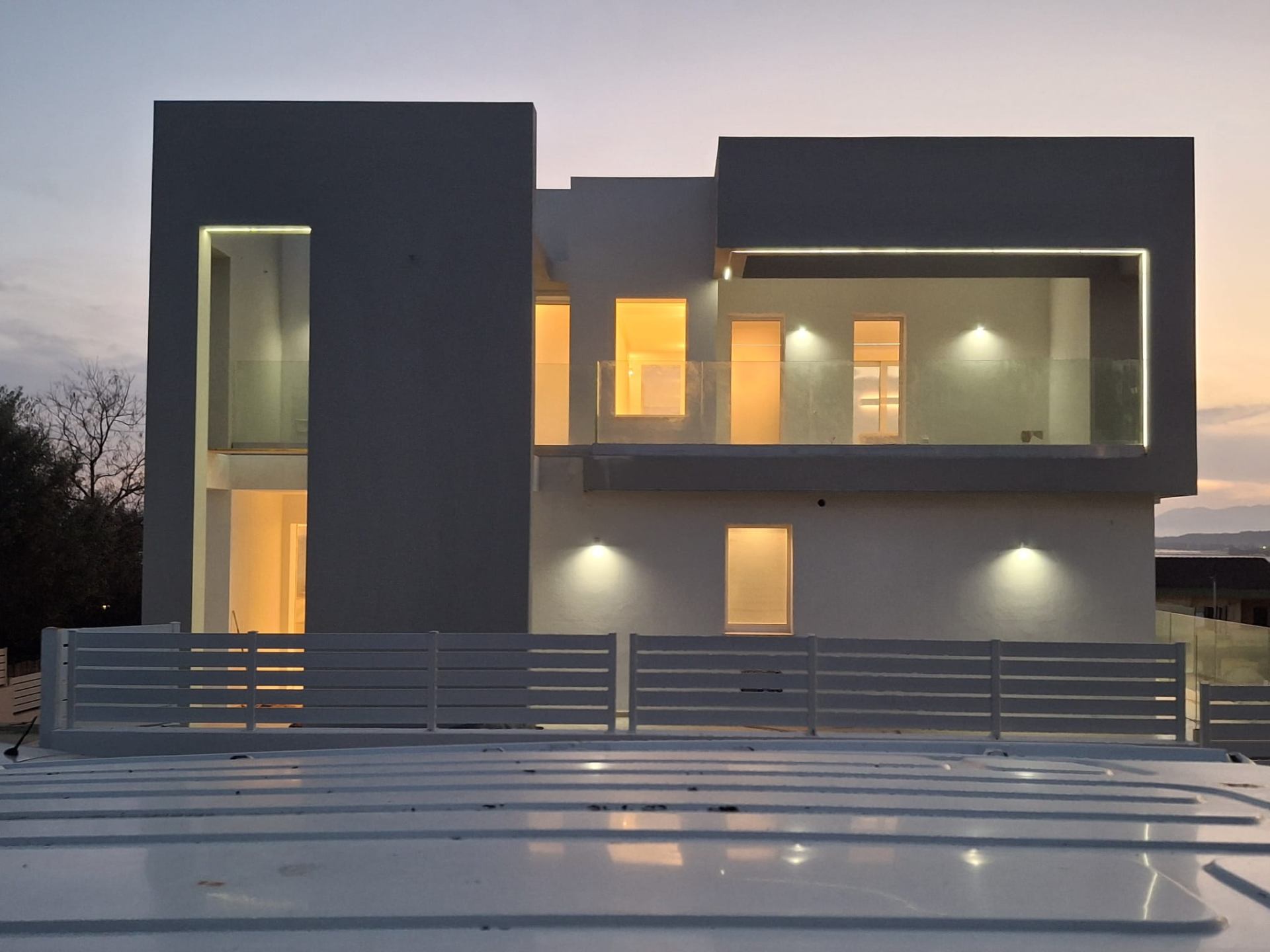 Facciata di villa moderna al tramonto con illuminazione architettonica.