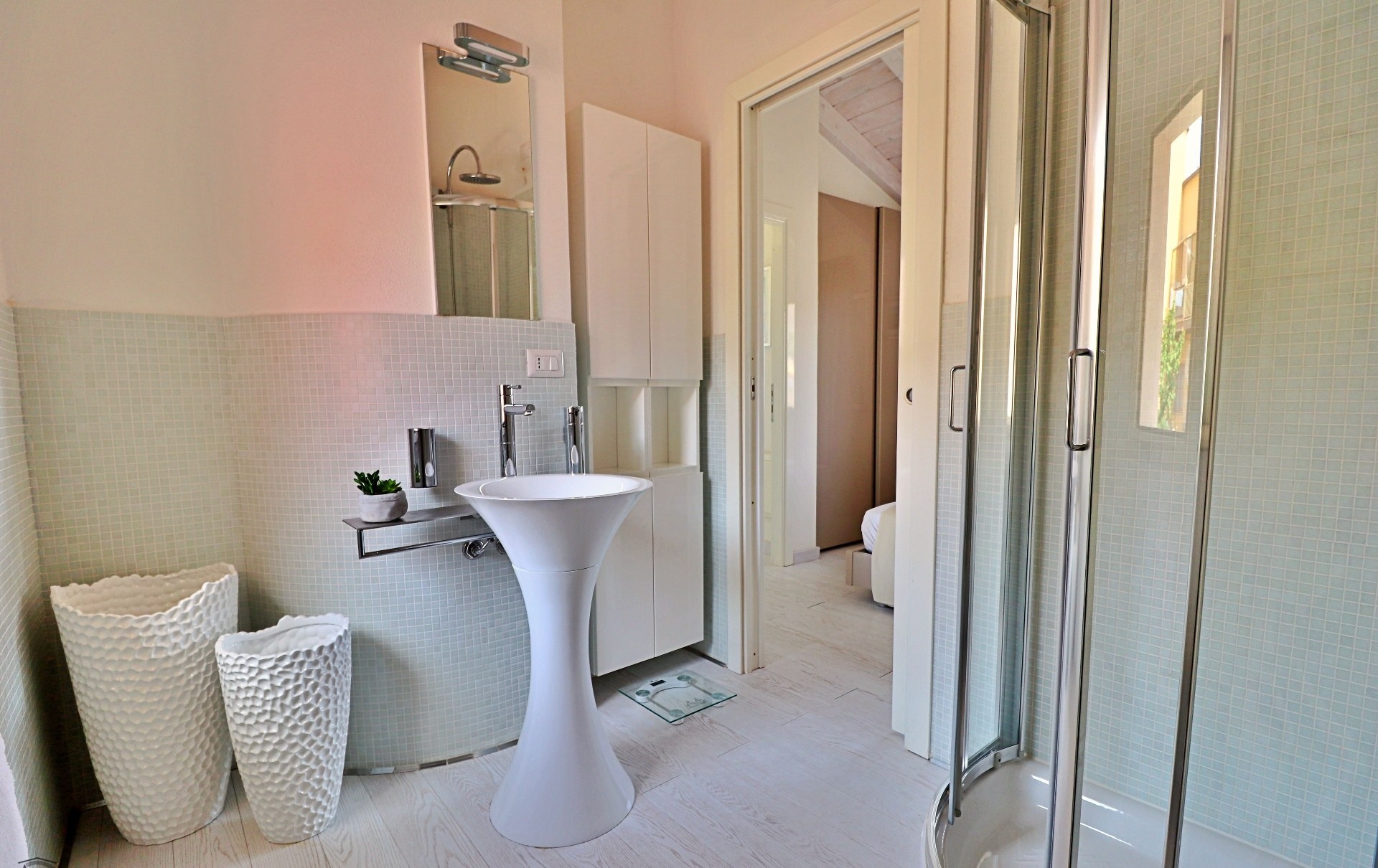 Bagno con lavabo scultoreo e finiture in mosaico.