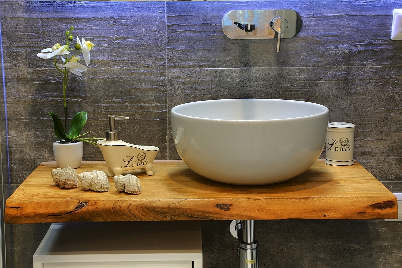 Bagno con lavabo scultoreo e finiture naturali.